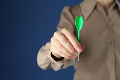 Photo of Woman holding dart on blue background, closeup