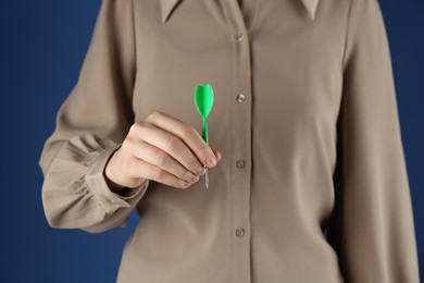 Photo of Woman holding dart on blue background, closeup