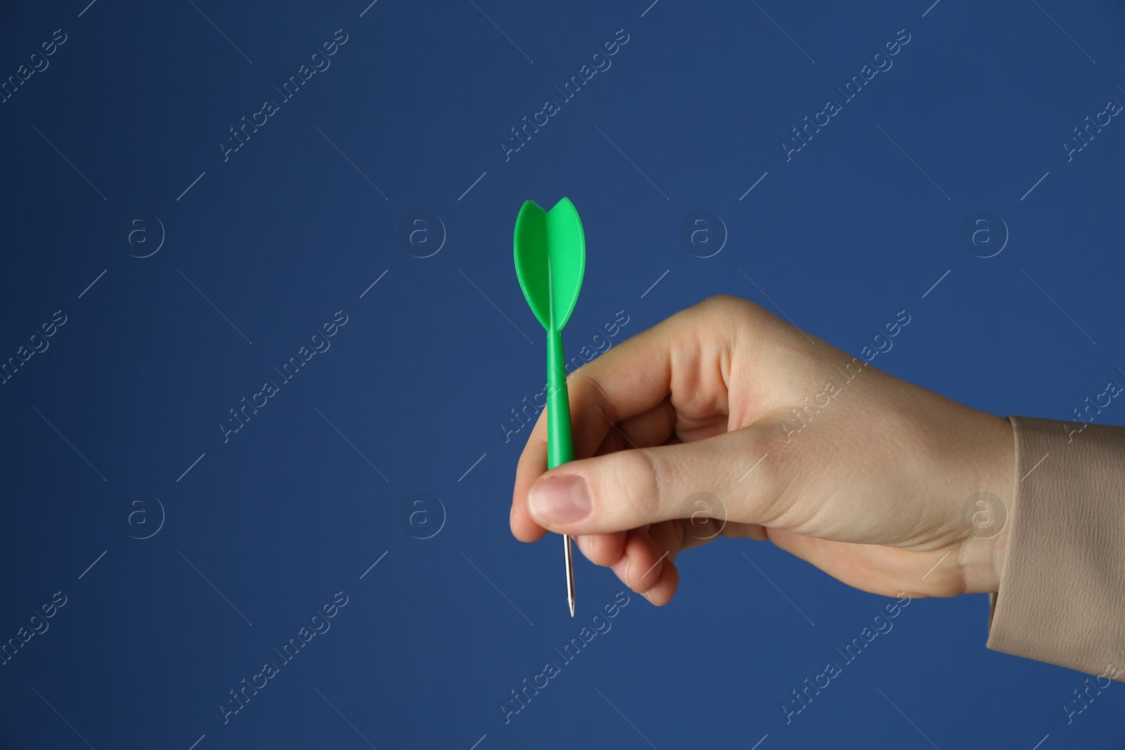 Photo of Woman holding dart on blue background, closeup. Space for text