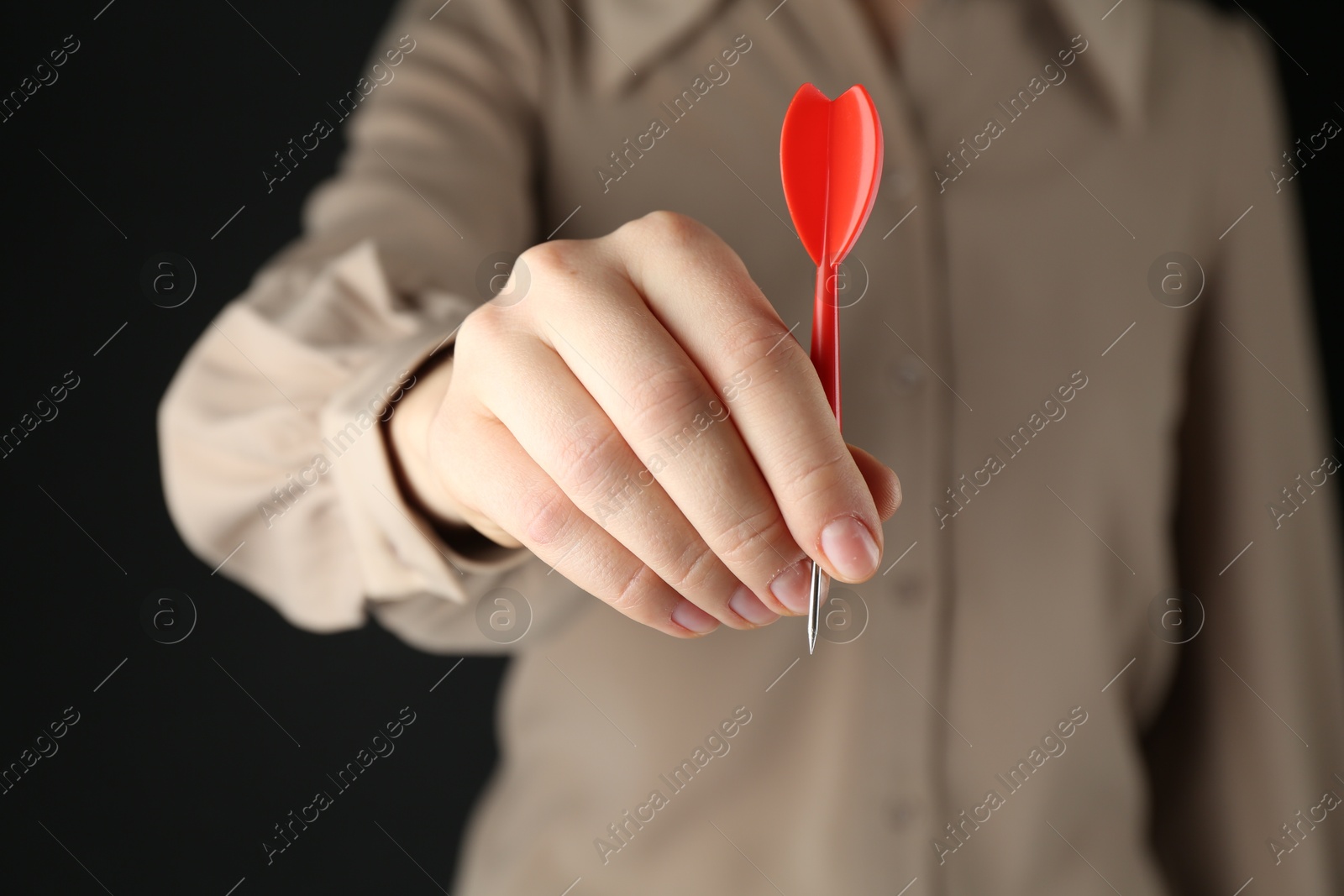 Photo of Woman holding dart on black background, closeup