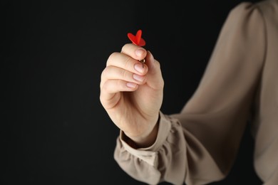 Photo of Woman holding dart on black background, closeup. Space for text