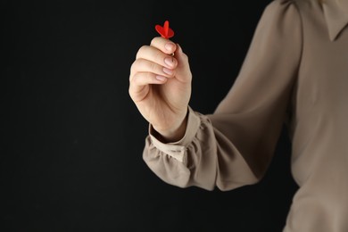 Photo of Woman holding dart on black background, closeup. Space for text