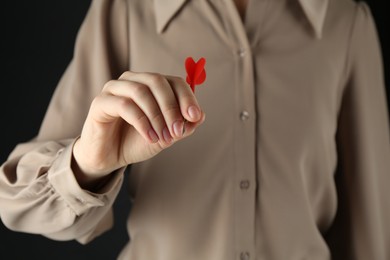 Photo of Woman holding dart on black background, closeup