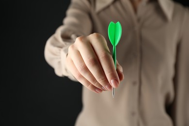 Photo of Woman holding dart on black background, closeup