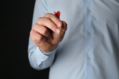 Photo of Man holding dart on black background, closeup