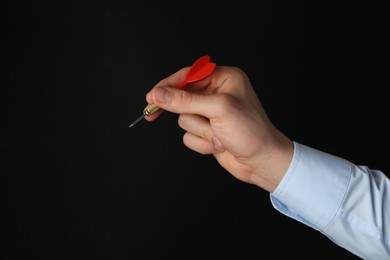 Photo of Man holding dart on black background, closeup. Space for text