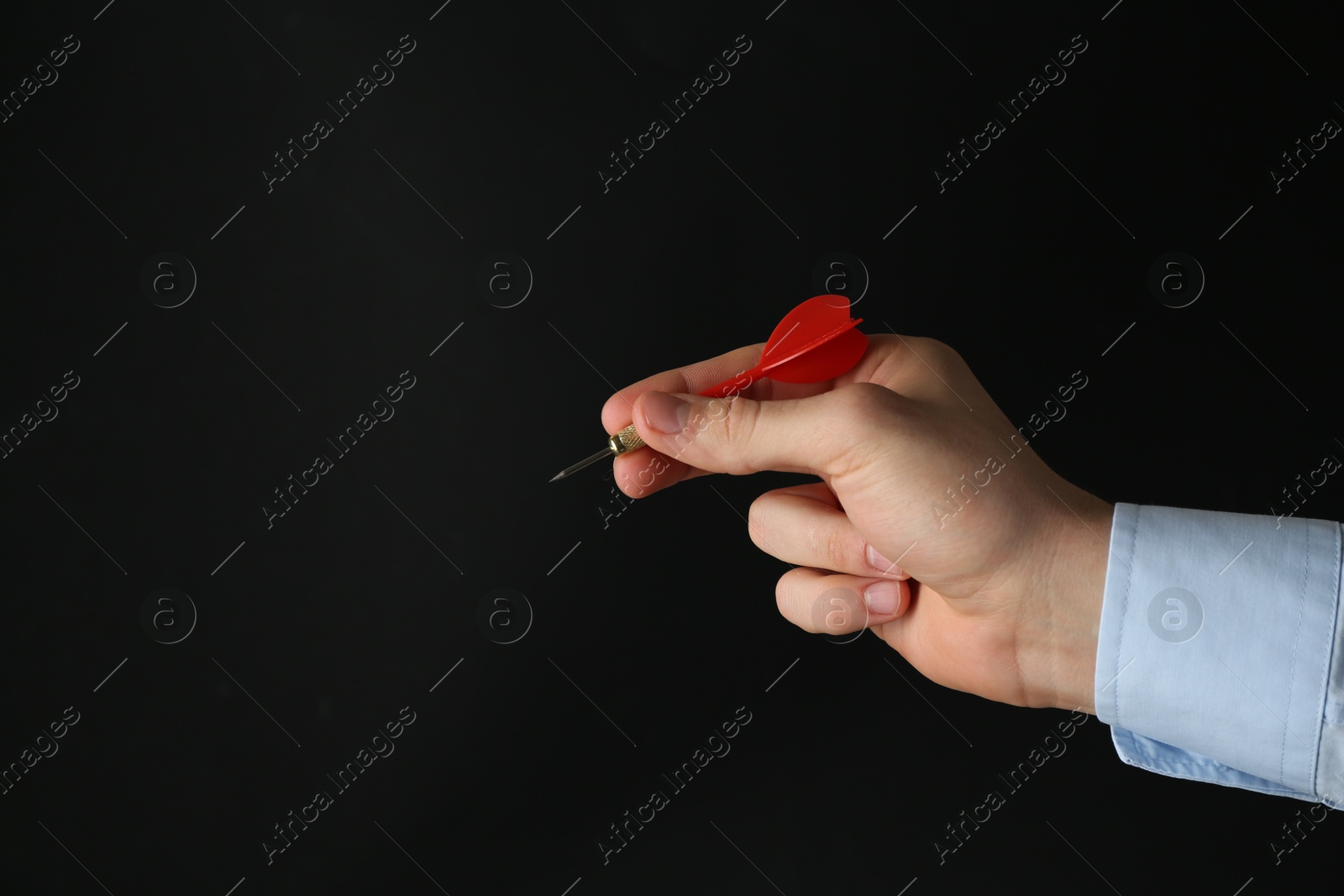 Photo of Man holding dart on black background, closeup. Space for text