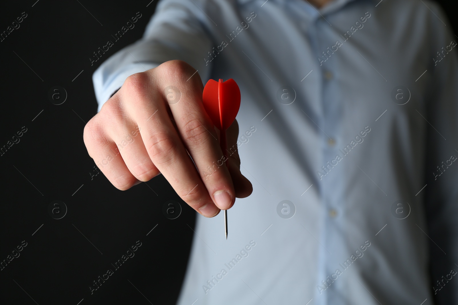 Photo of Man holding dart on black background, closeup