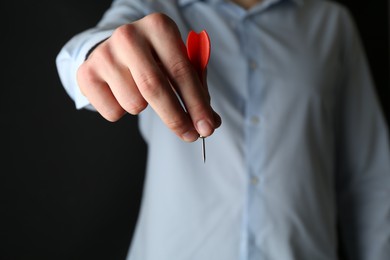 Photo of Man holding dart on black background, closeup