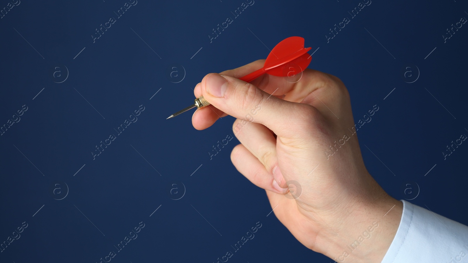 Photo of Man holding dart on blue background, closeup. Space for text