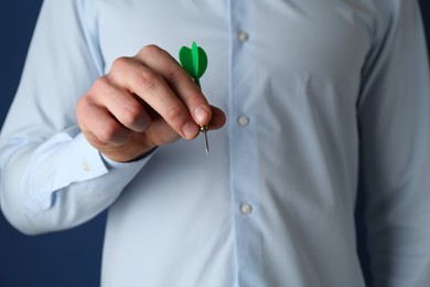 Photo of Man holding dart on blue background, closeup