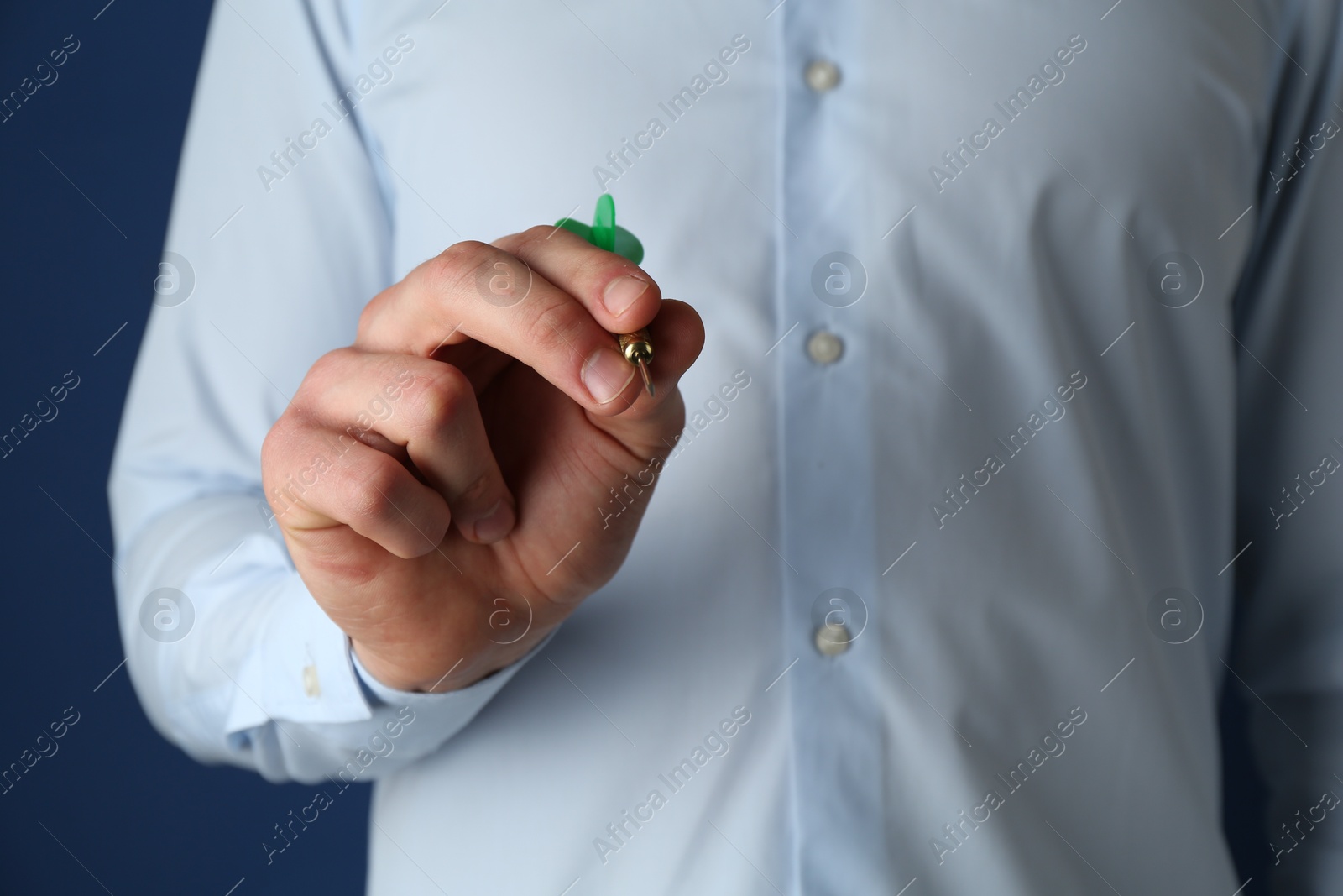 Photo of Man holding dart on blue background, closeup