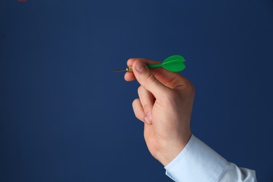 Photo of Man holding dart on blue background, closeup. Space for text