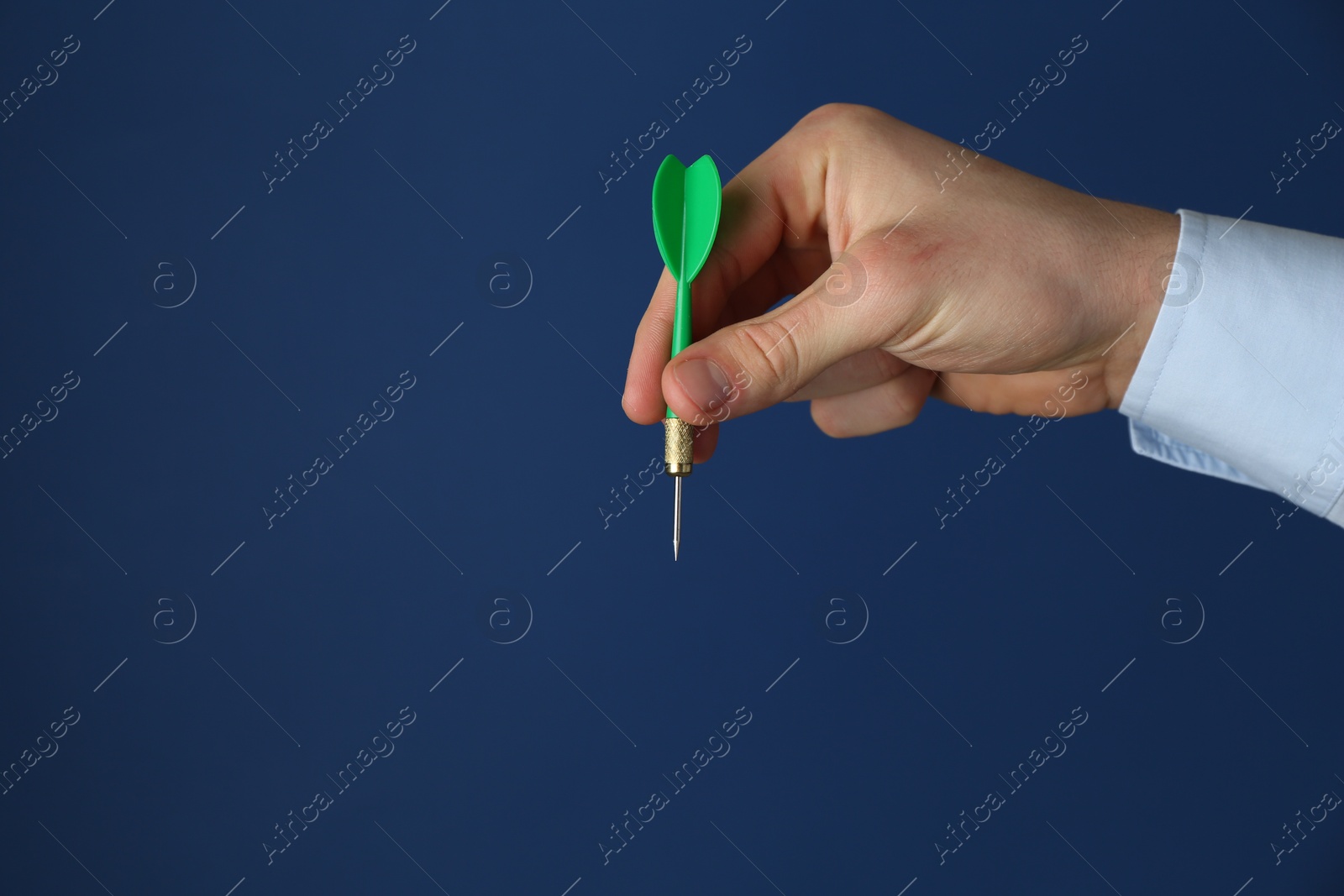 Photo of Man holding dart on blue background, closeup. Space for text