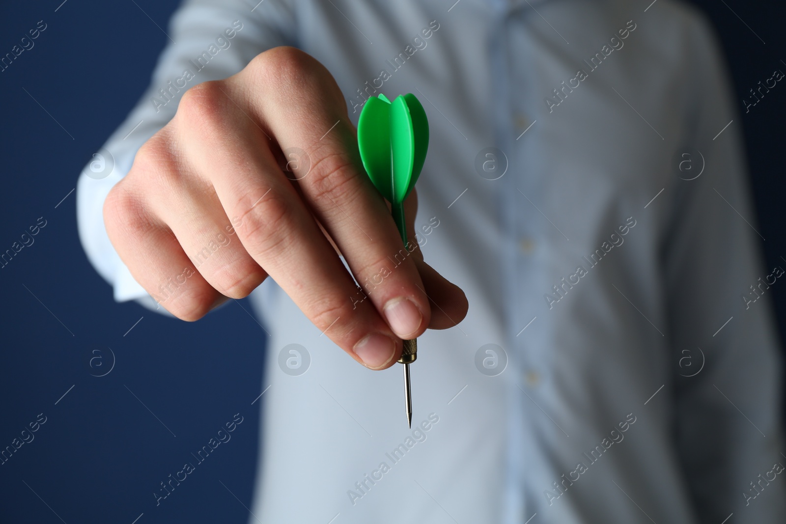 Photo of Man holding dart on blue background, closeup