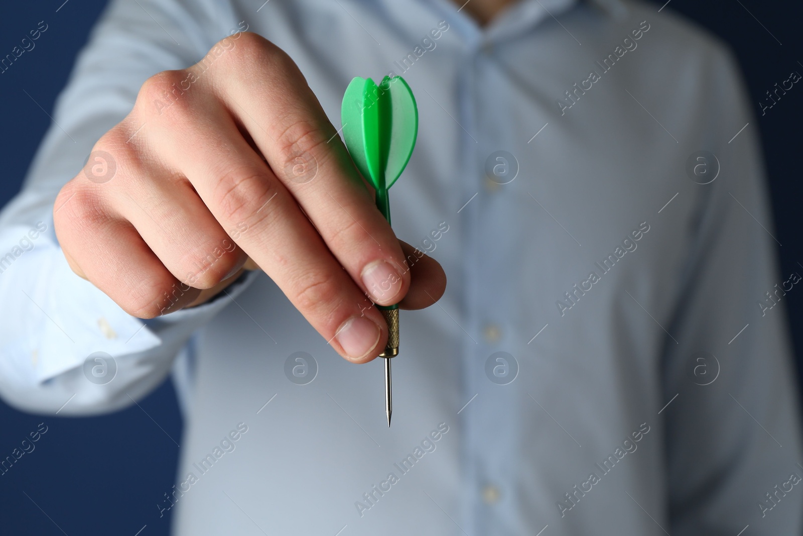 Photo of Man holding dart on blue background, closeup