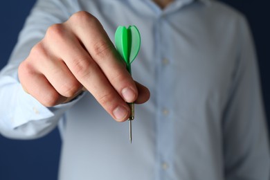 Photo of Man holding dart on blue background, closeup