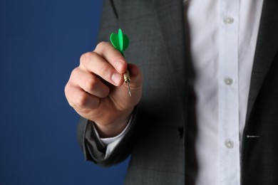 Photo of Man holding dart on blue background, closeup