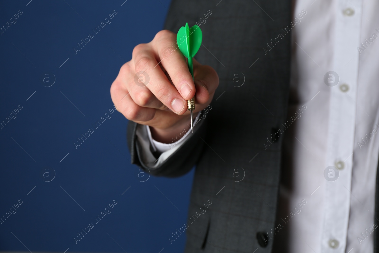 Photo of Man holding dart on blue background, closeup