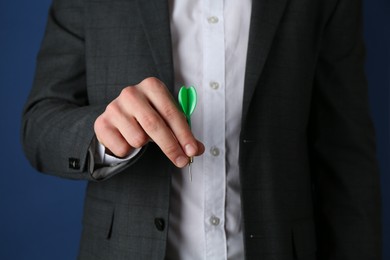 Photo of Man holding dart on blue background, closeup