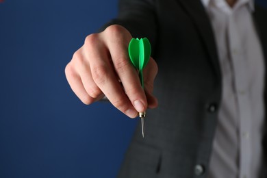 Photo of Man holding dart on blue background, closeup