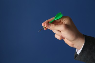 Photo of Man holding dart on blue background, closeup. Space for text