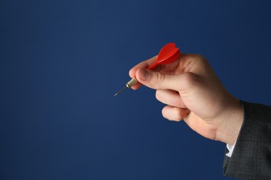 Photo of Man holding dart on blue background, closeup. Space for text