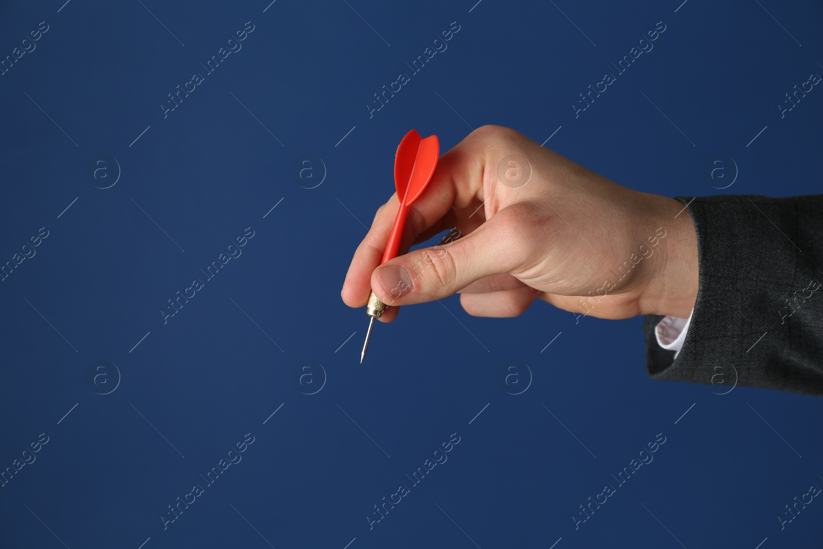 Photo of Man holding dart on blue background, closeup. Space for text