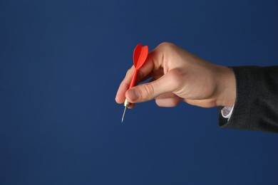 Photo of Man holding dart on blue background, closeup. Space for text