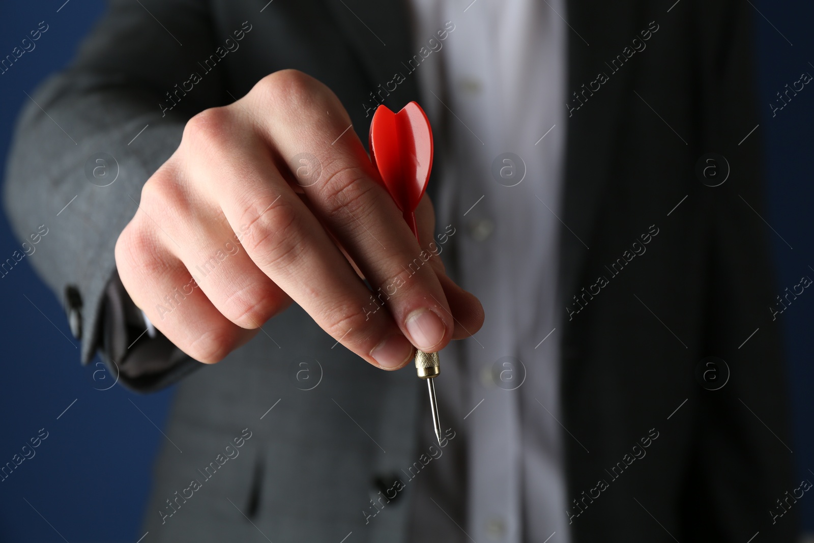 Photo of Man holding dart on blue background, closeup