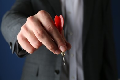 Photo of Man holding dart on blue background, closeup