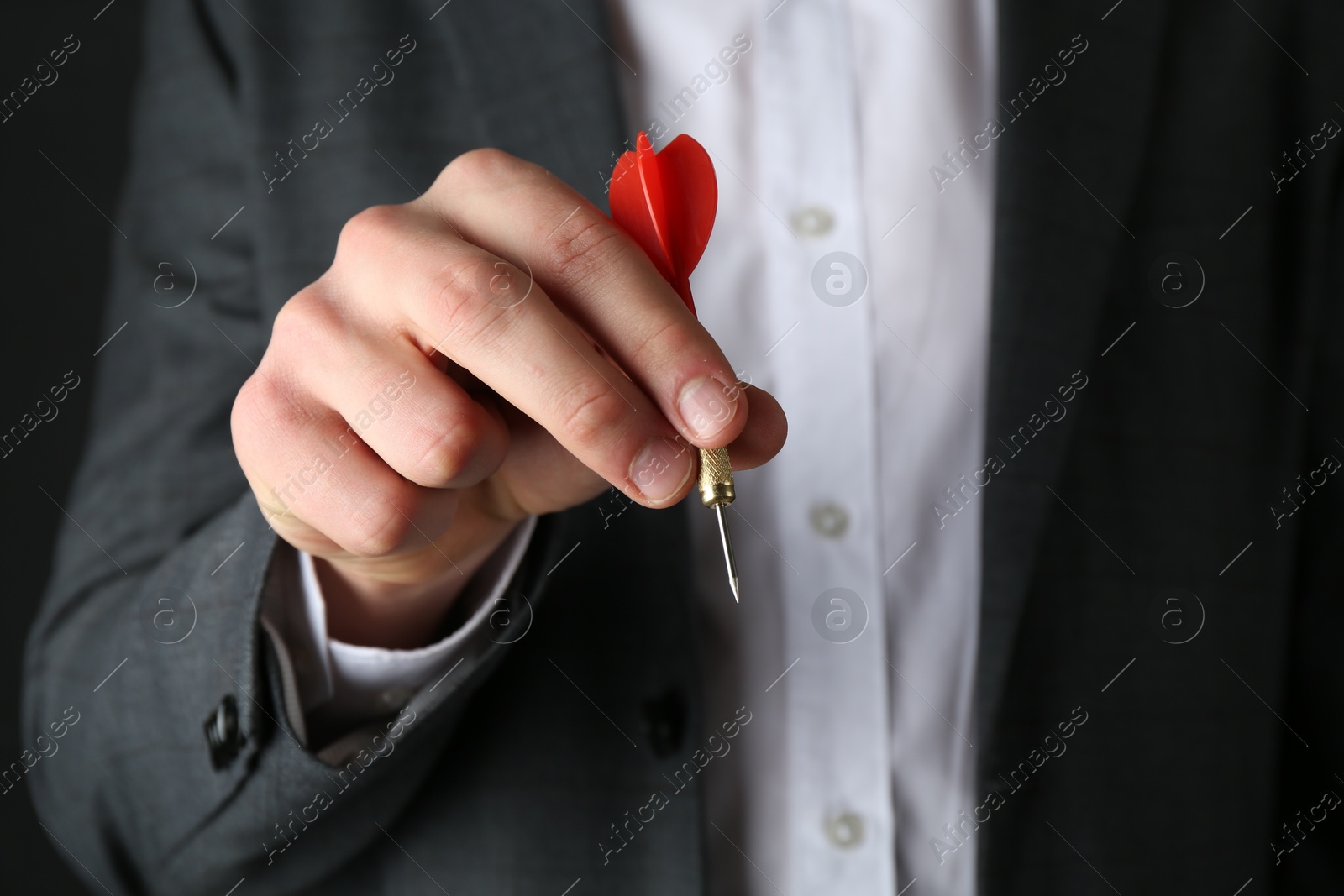 Photo of Man holding dart on black background, closeup