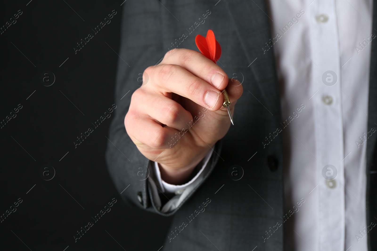 Photo of Man holding dart on black background, closeup