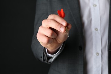 Photo of Man holding dart on black background, closeup