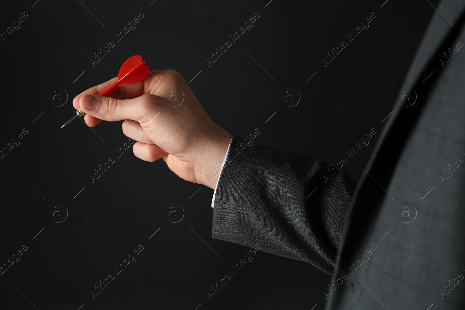 Photo of Man holding dart on black background, closeup