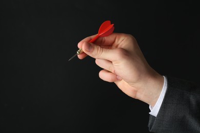 Photo of Man holding dart on black background, closeup. Space for text