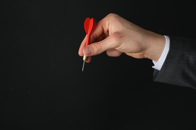 Photo of Man holding dart on black background, closeup. Space for text