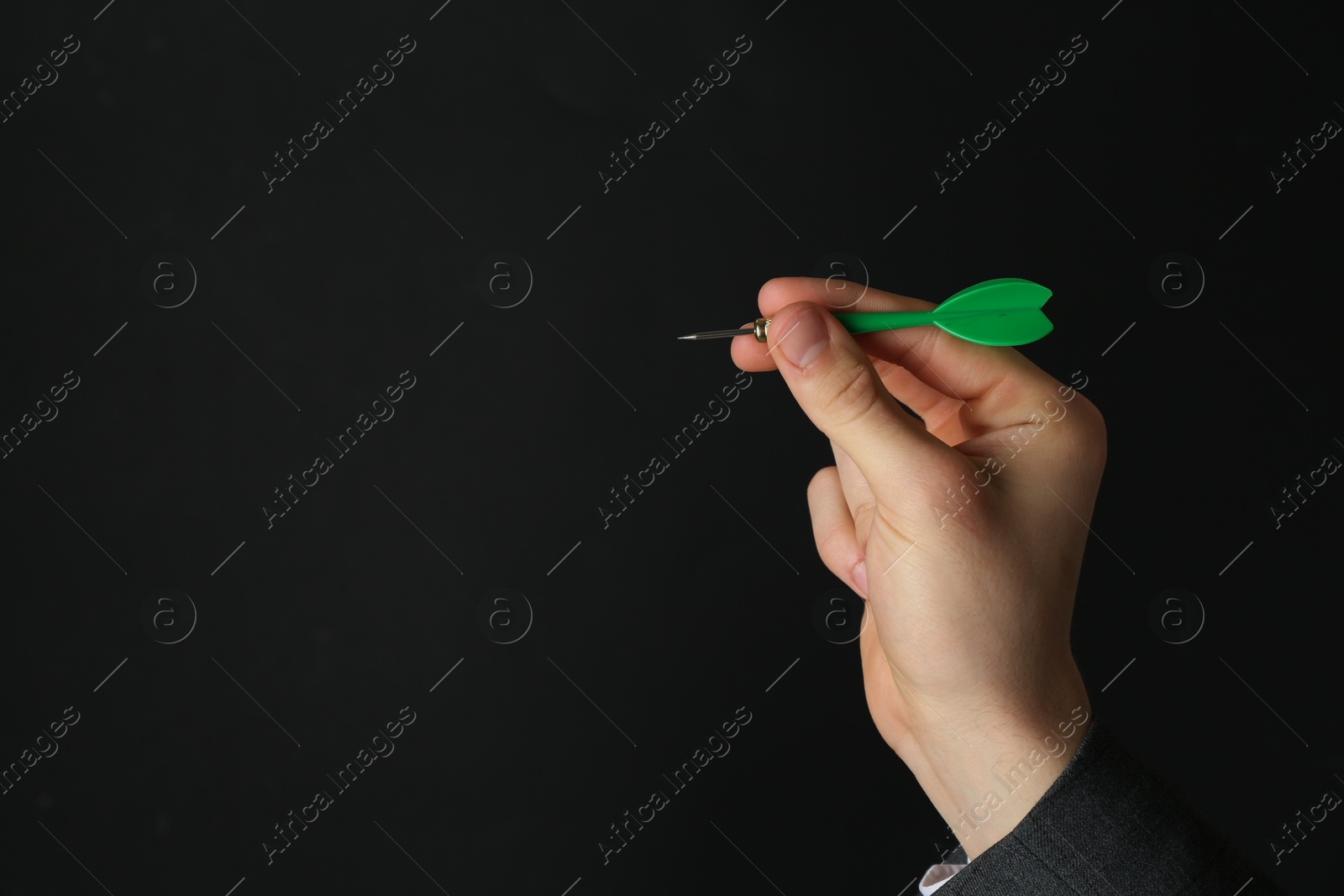 Photo of Man holding dart on black background, closeup. Space for text