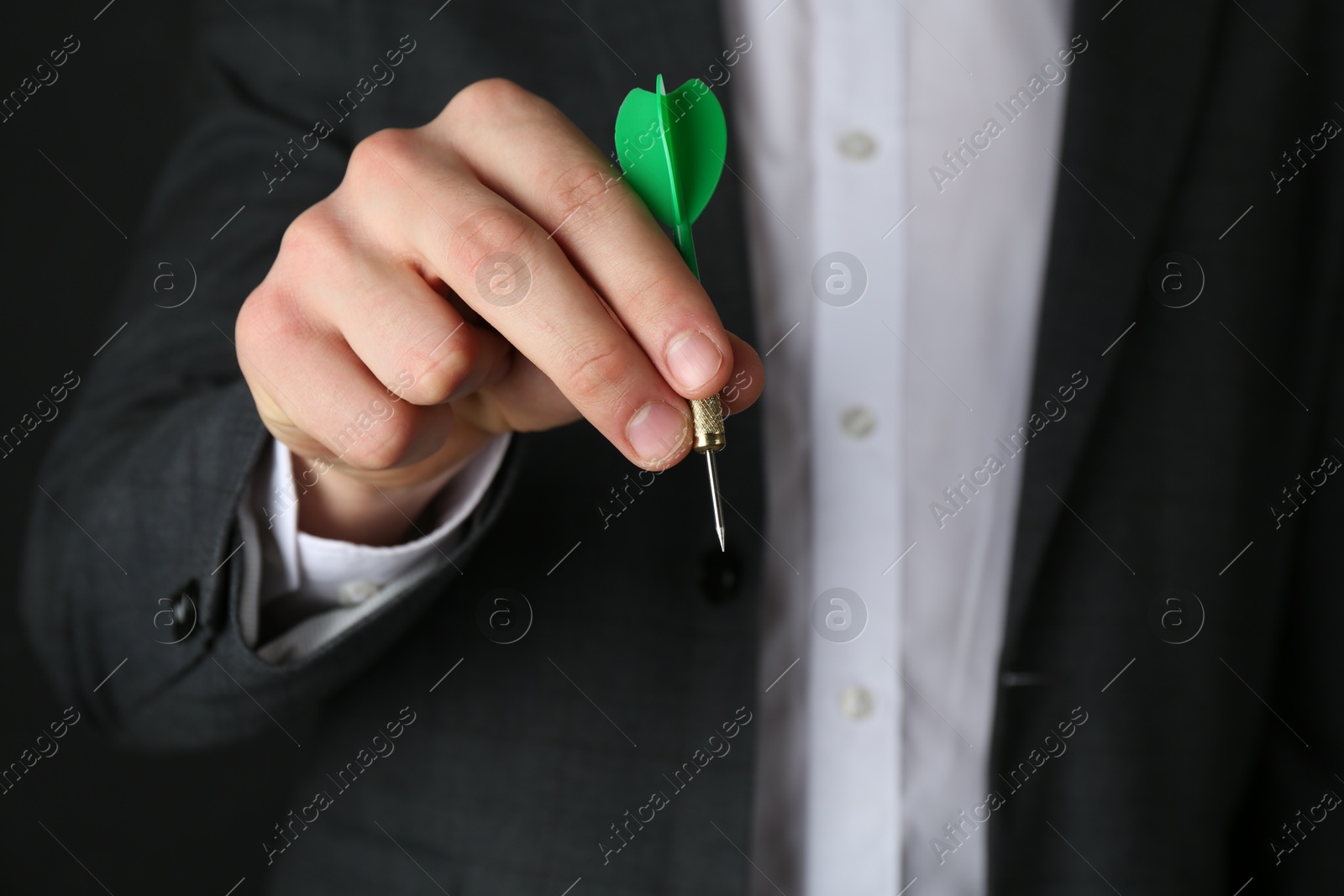 Photo of Man holding dart on black background, closeup