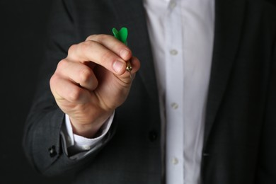 Photo of Man holding dart on black background, closeup