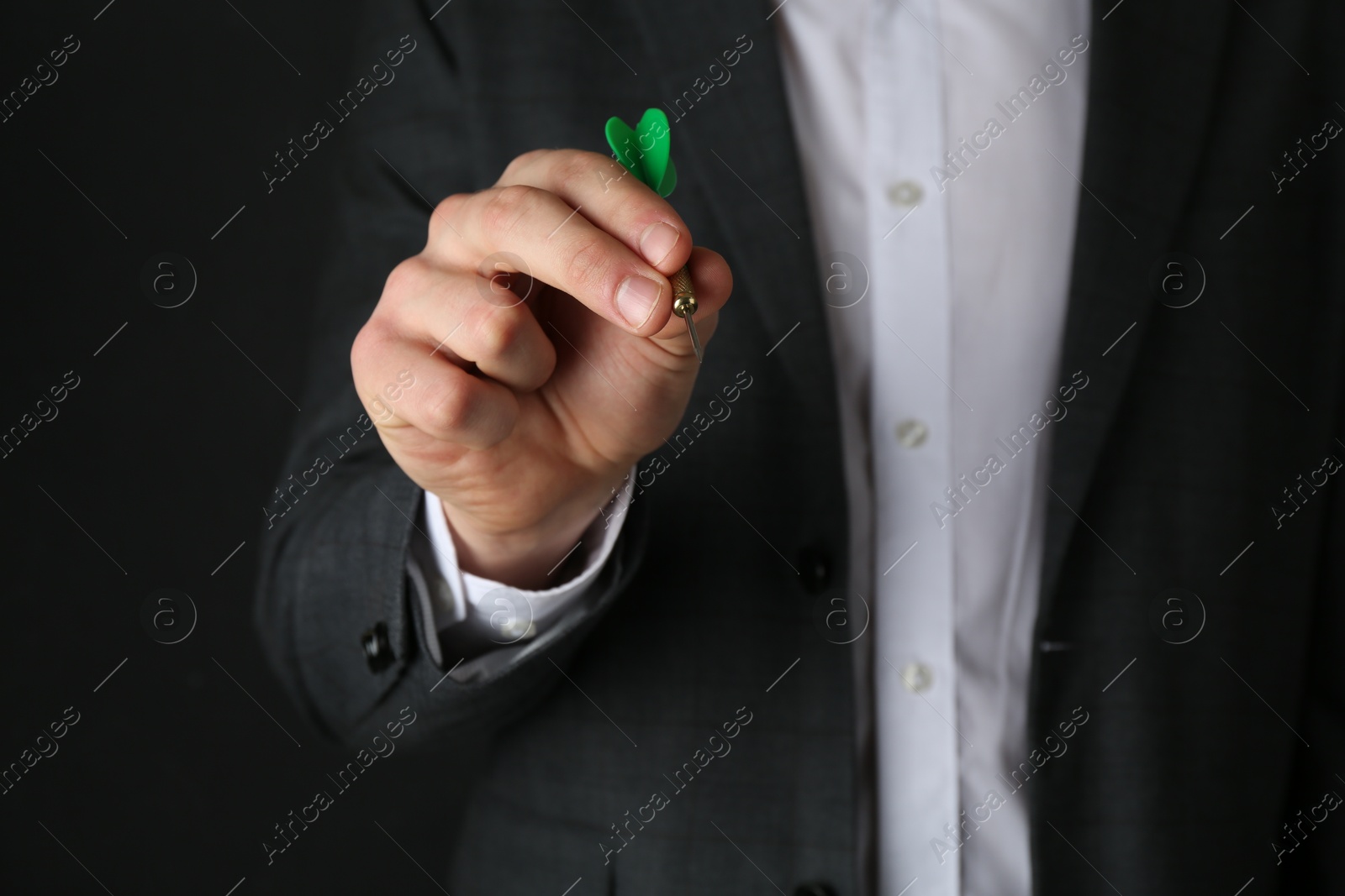 Photo of Man holding dart on black background, closeup