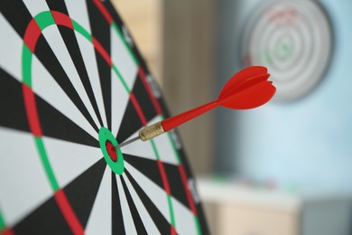 Photo of Red arrow hitting target on dart board indoors, closeup