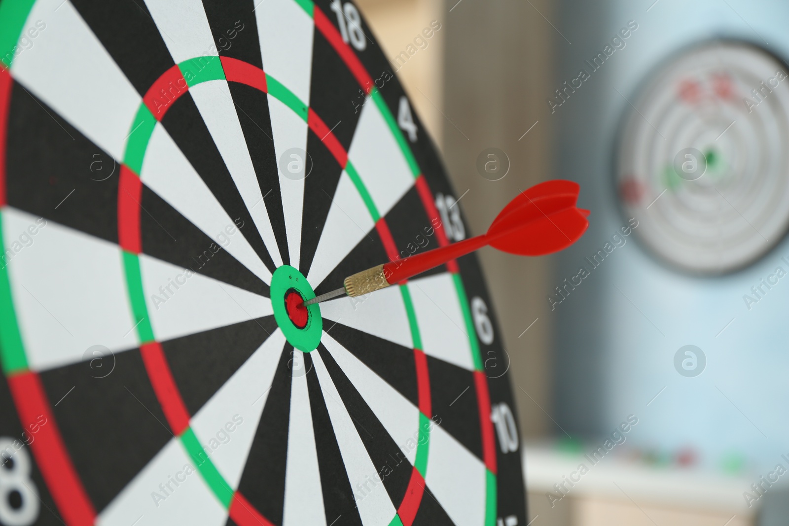 Photo of Red arrow hitting target on dart board indoors, closeup