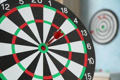 Photo of Red arrow hitting target on dart board indoors, closeup