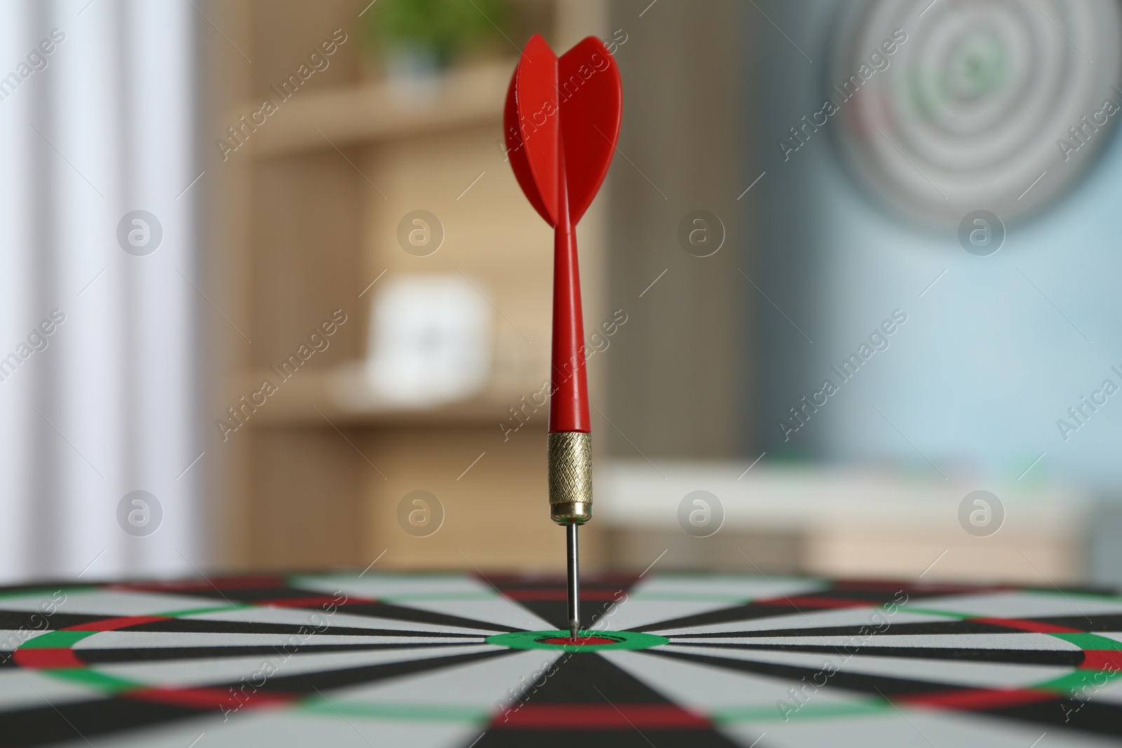 Photo of Red arrow hitting target on dart board indoors, closeup