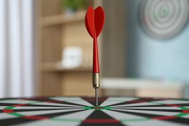 Photo of Red arrow hitting target on dart board indoors, closeup