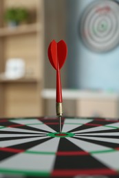 Photo of Red arrow hitting target on dart board indoors, closeup