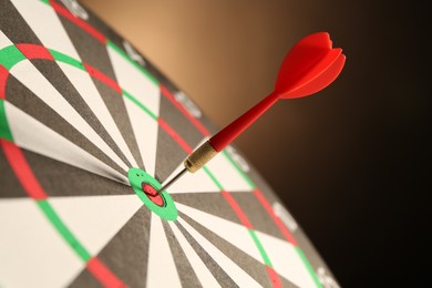 Photo of Red arrow hitting target on dart board against black background, closeup