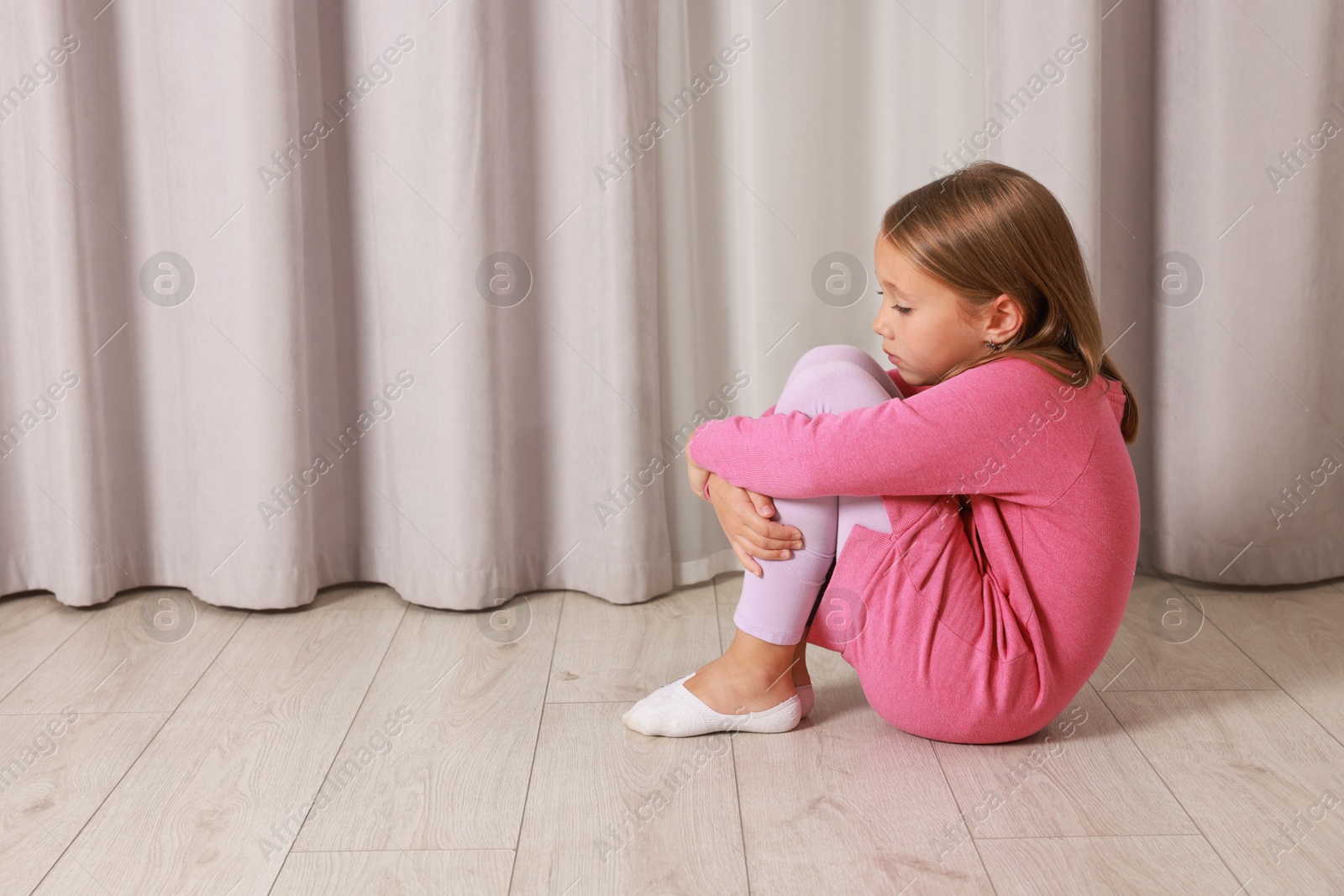 Photo of Autism concept. Lonely little girl sitting on floor at home, space for text