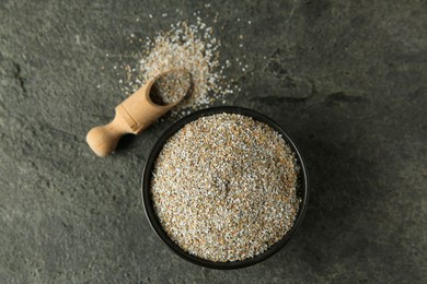 Photo of Fresh rye bran and scoop on grey textured table, flat lay